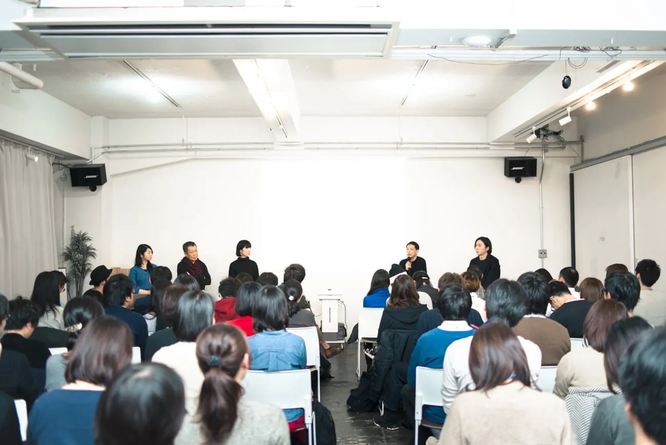 白い会場を埋めた参加者が、前に並んだ登壇者のトークを聞いている